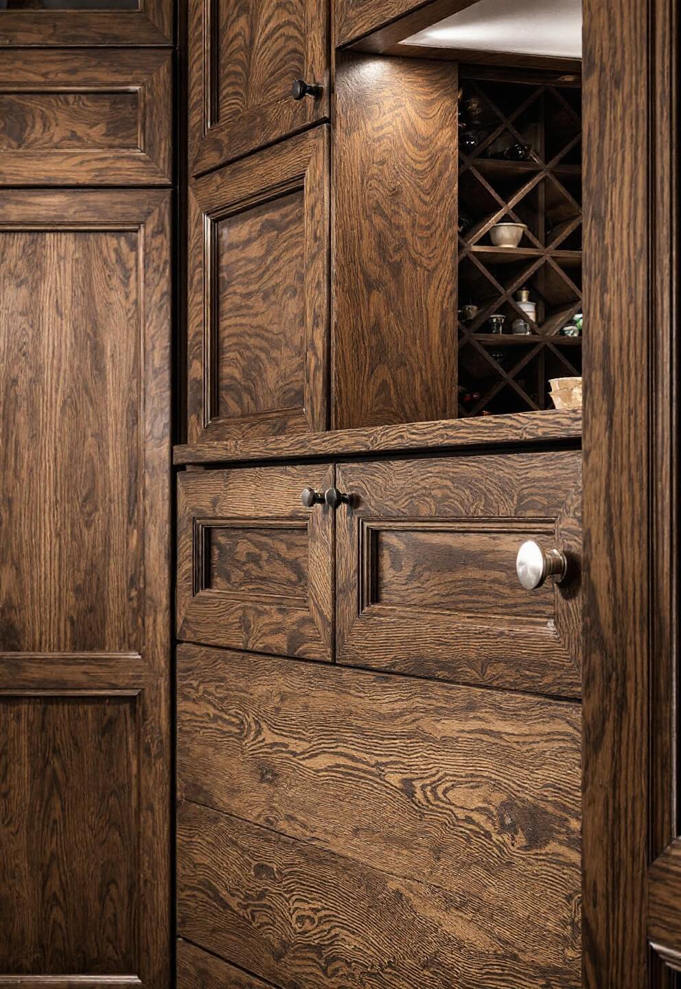 Detailed view of an 8x10ft butler's pantry with quarter-sawn oak cabinets with coffee stain, built-in wine storage, custom plate racks, and side lighting highlighting wood texture.