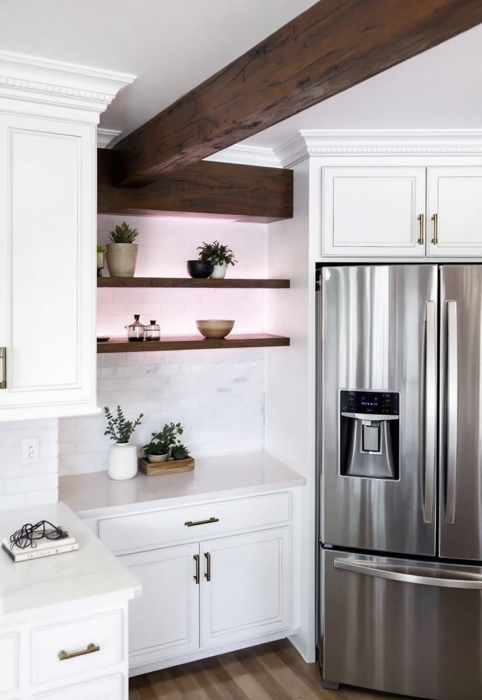 Modern farmhouse kitchen with smart home tech in brass switch plates, stainless appliances against white distressed cabinetry, and atmospheric LED lighting in beam work.