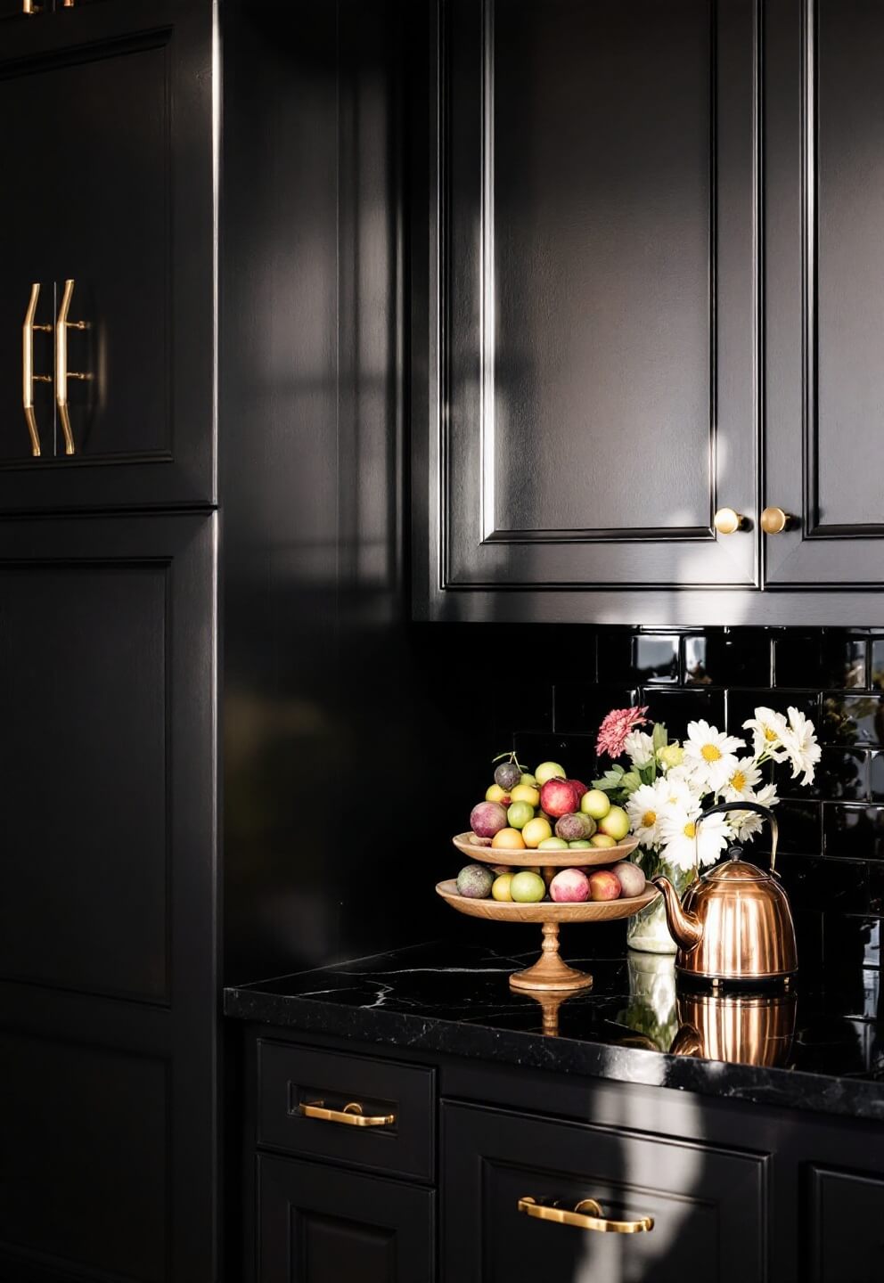 Dark cabinets with brass hardware meeting a black quartz countertop, wooden fruit bowl and antique copper kettle in golden hour lighting