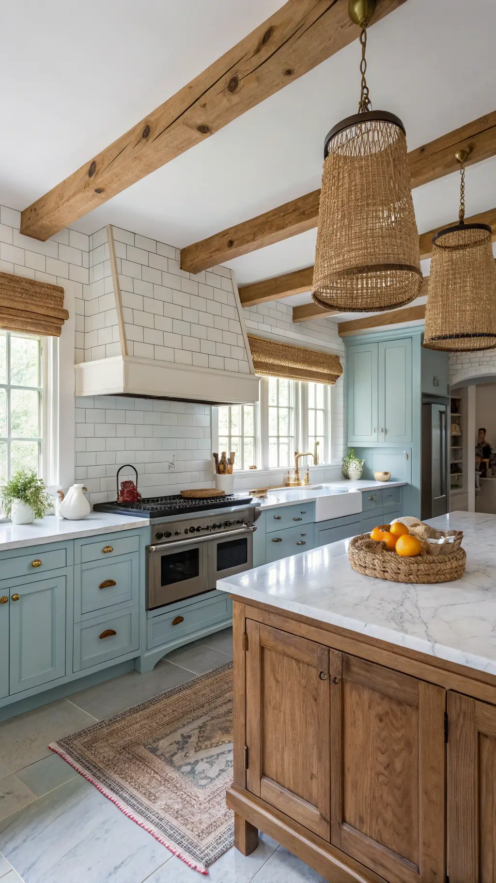Nostalgic and comfortable powder blue kitchen with exposed wooden beams, antique brass cup pulls, Carrara marble counters and subway tile walls, and vintage-style range in cream at midday
